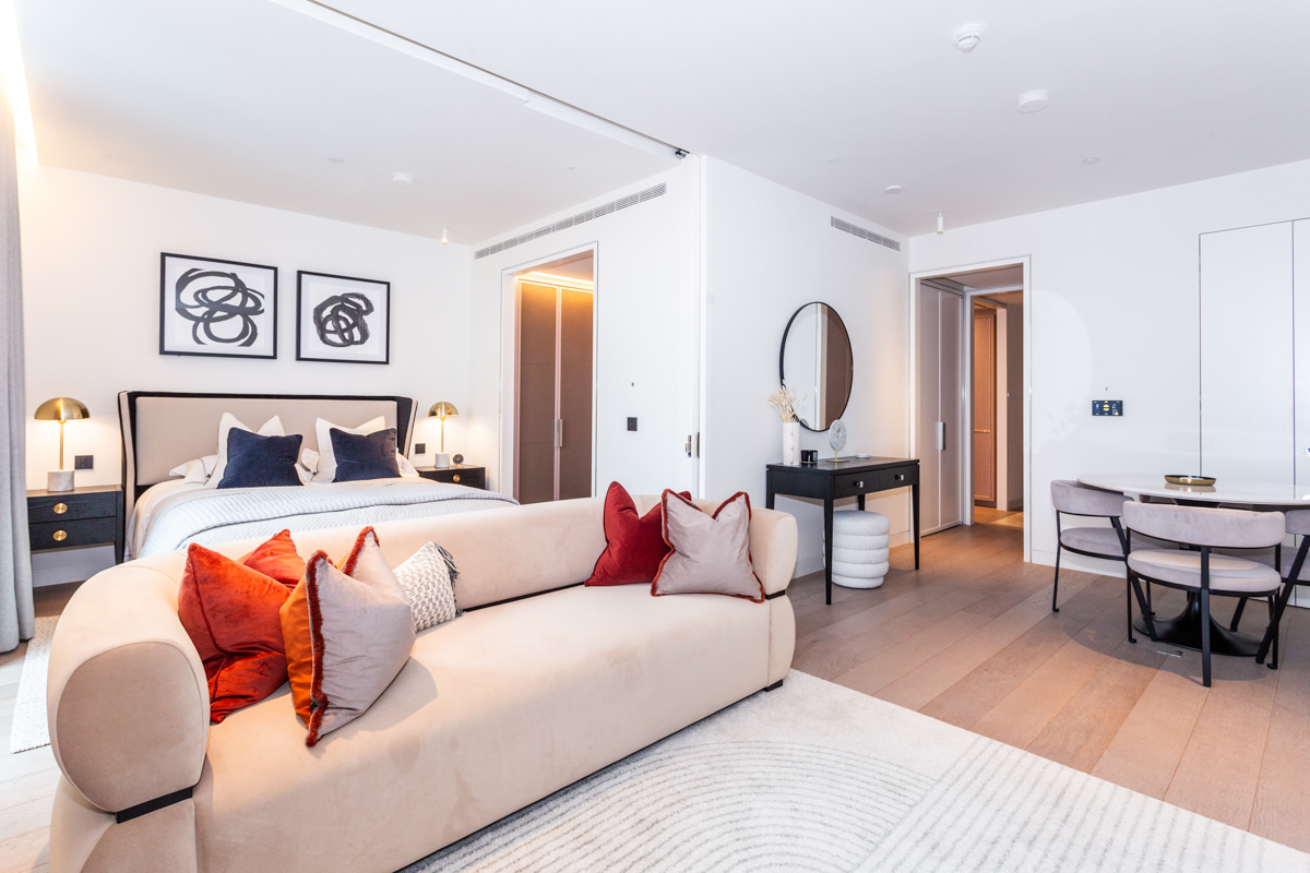 Elegant bedroom with neutral tones, plush sofa, and contemporary decor.