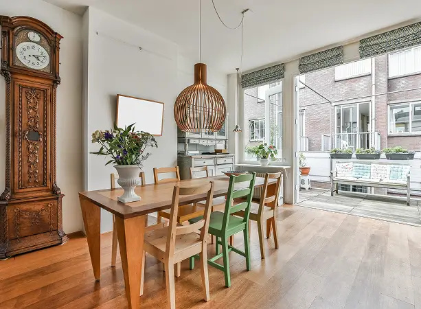 Cozy dining area with wooden table, mixed chairs, and antique clock.