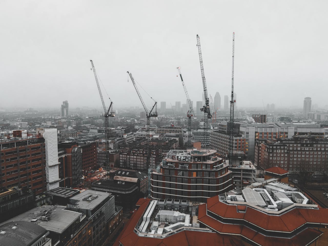 City skyline with construction cranes on a foggy day.