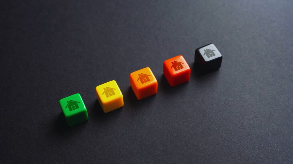 Infographic from Ernest Brooks: Five colorful cubes with house icons in ascending energy efficiency order: green (A), yellow (B/C), orange (D), red (E), black (F/G). Image shows cubes on dark background.